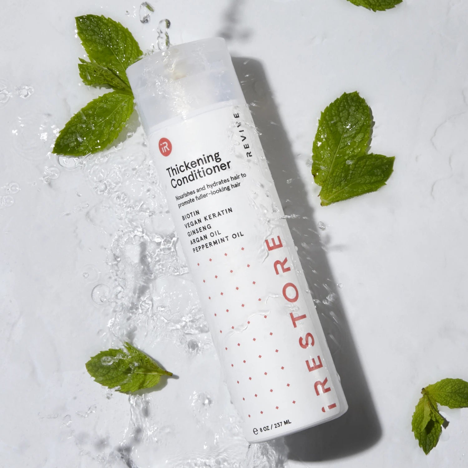 Top down view image of the Thickening Conditioner surrounded by water and fresh mint leaves.