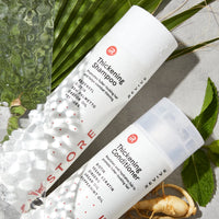 Top down view image showing the Thickening Shampoo and Conditioner with ginseng and leaves around it.