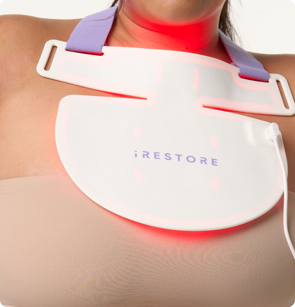 Close up shop of woman's neck whil wearing the iRESTORE LED neck and chest mask with red light turned on