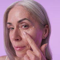 Woman applying anti-aging eye cream on her face using one finger