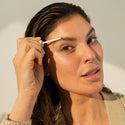 Close up shot image of a woman while applying the Eyebrow Enhancing Serum.