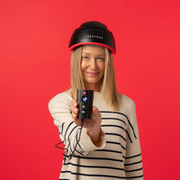 Image of a woman wearing the Elite helmet device while holding the rechargeable battery pack.