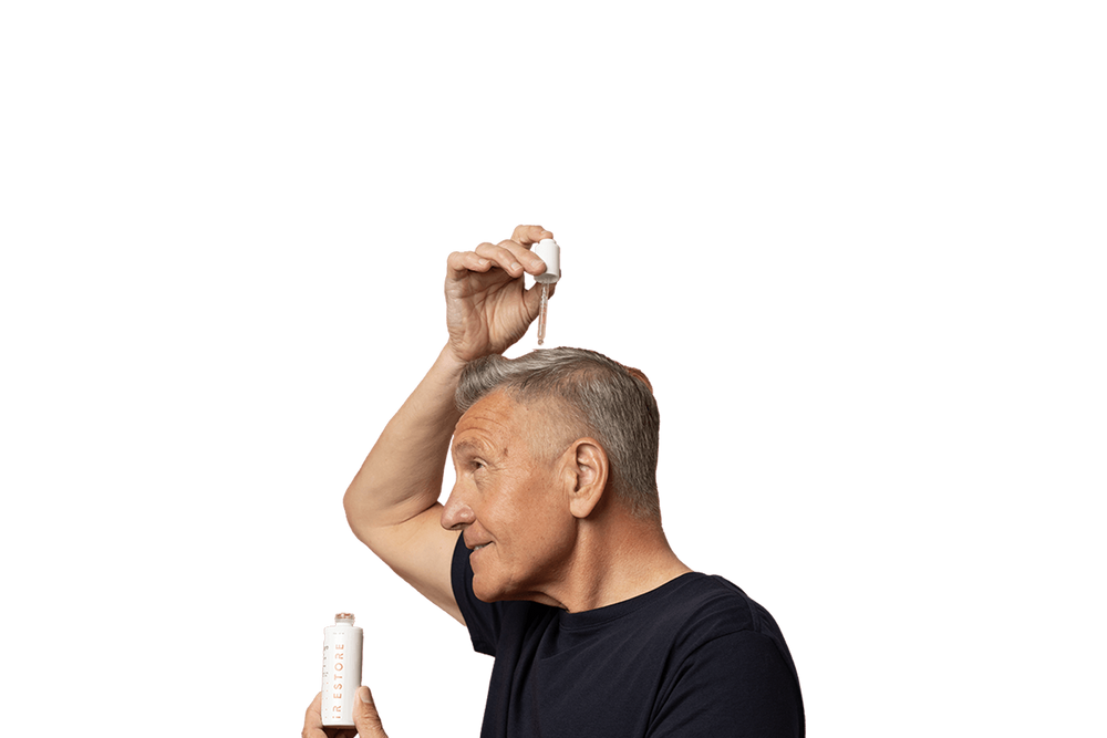 Mature man putting droplets of growth activator serum on his hair