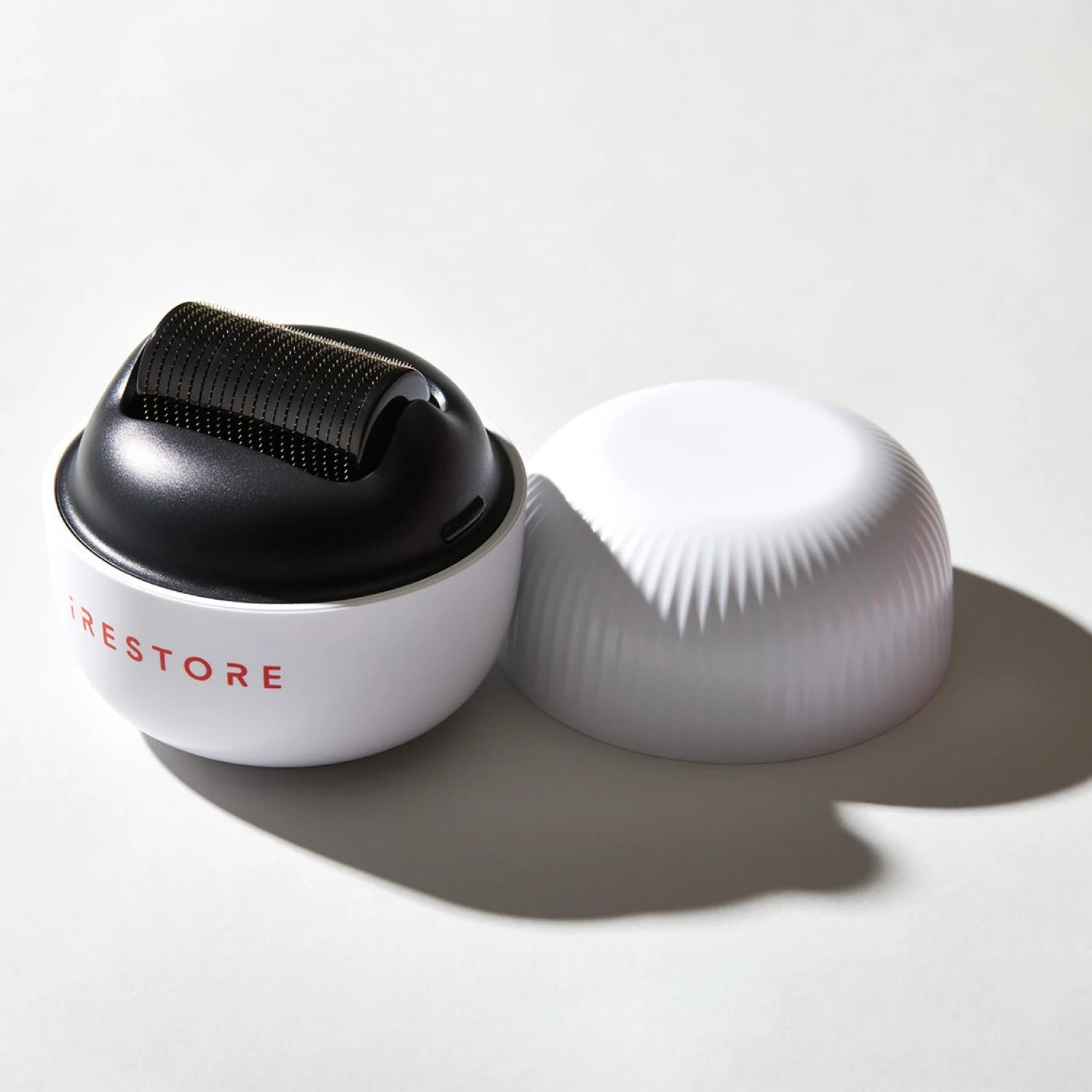 Image of the ScalpStim Derma Roller placed on top of a table with its cap beside it.