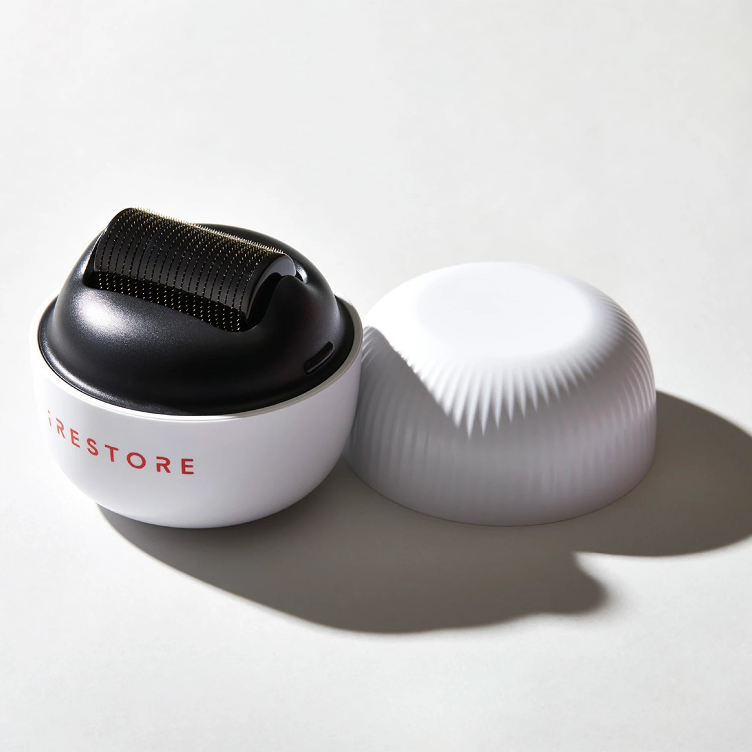 Image of the ScalpStim Derma Roller placed on top of a table with its cap beside it.