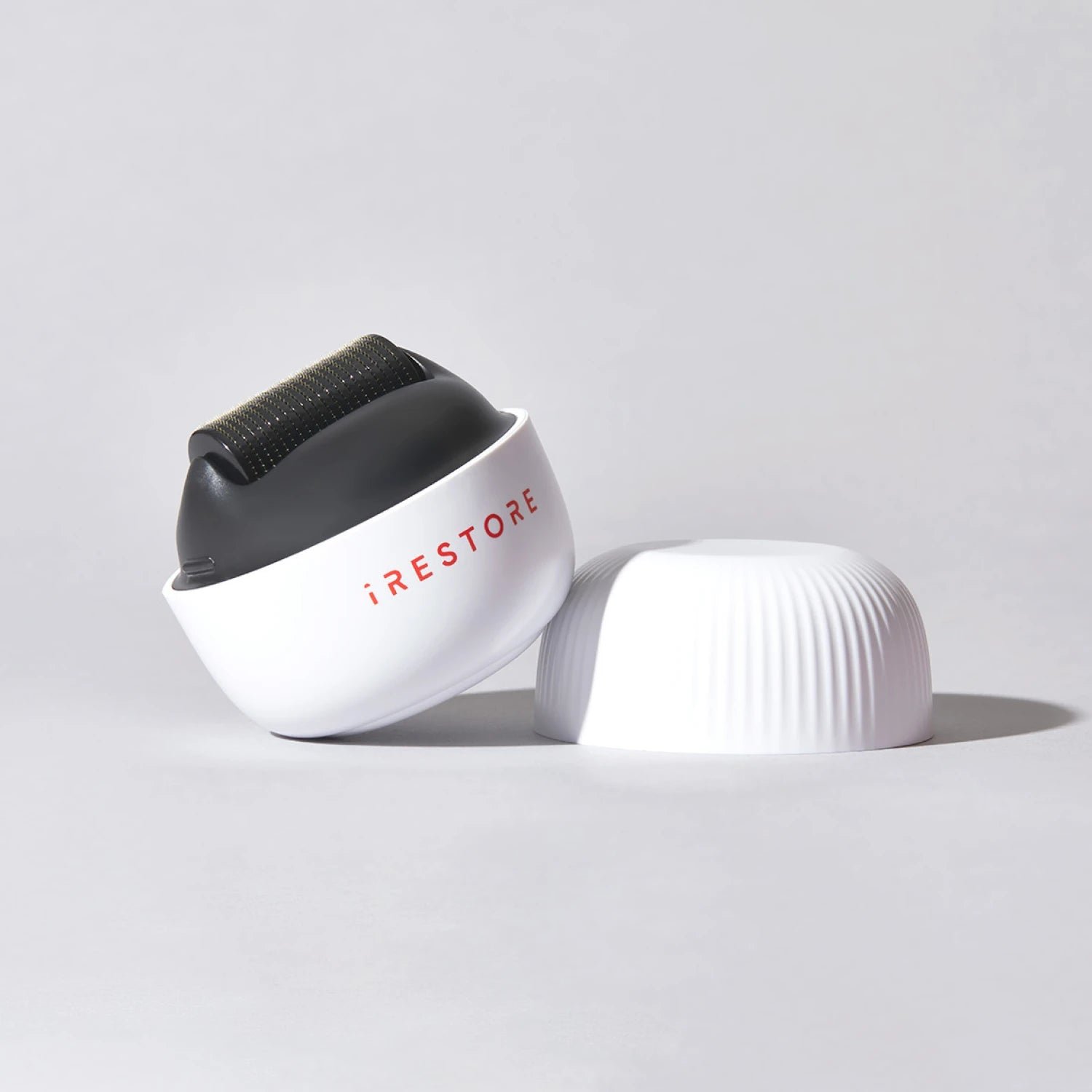 Image of the ScalpStim Derma Roller placed on top of a table with its cap beside it.