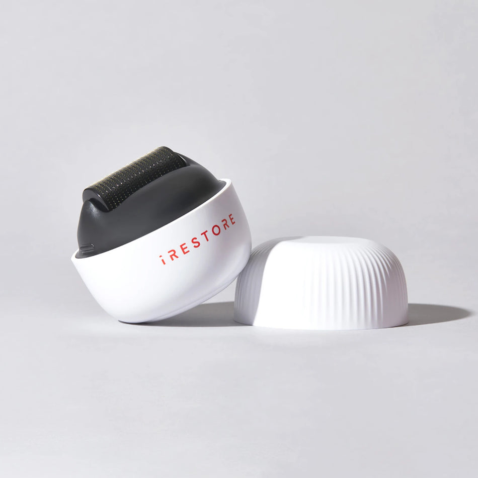 Image of the ScalpStim Derma Roller placed on top of a table with its cap beside it.