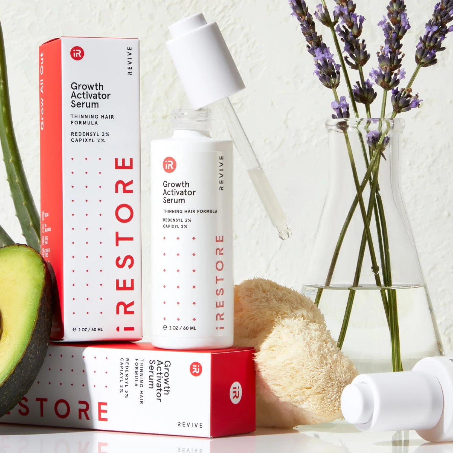 Image showing the Growth Activator Serum with its packaging box beside it and an avocado, mushroom, aloe vera and lavander are in the background.