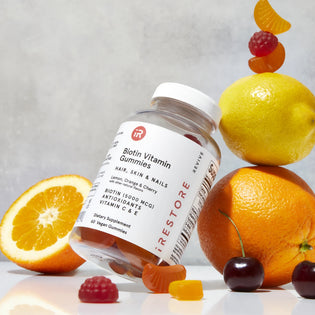 Image of the Biotin Vitamin Gummies with orange, lemon, cherries and vitamin gummies in the background.