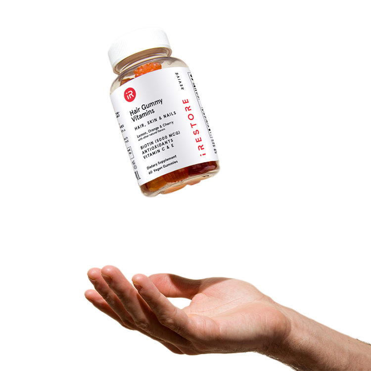 Biotin gummies bottle in mid air with a hand below to catch it.