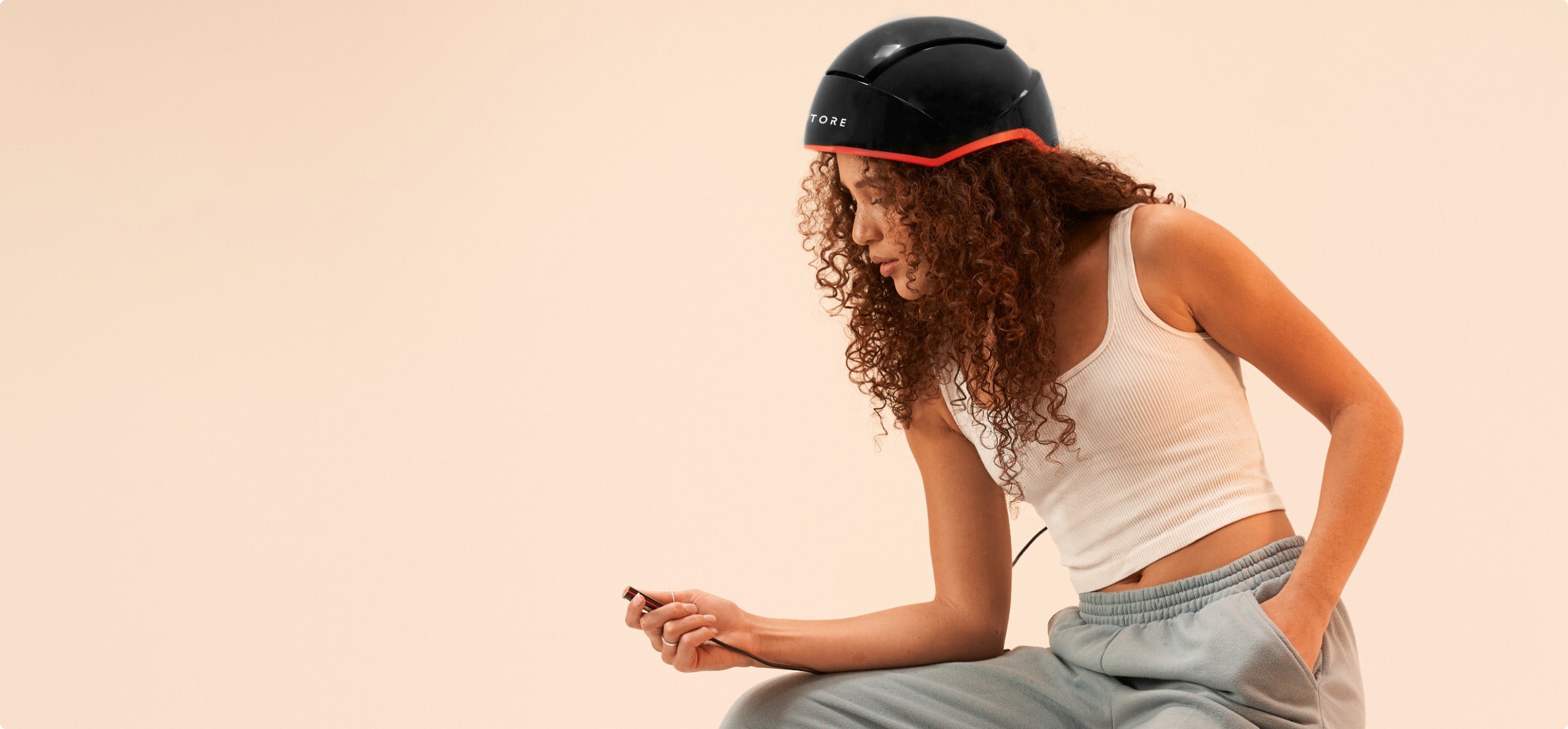 Image of a sitting woman wearing the Elite device and holding the remote controller. 
