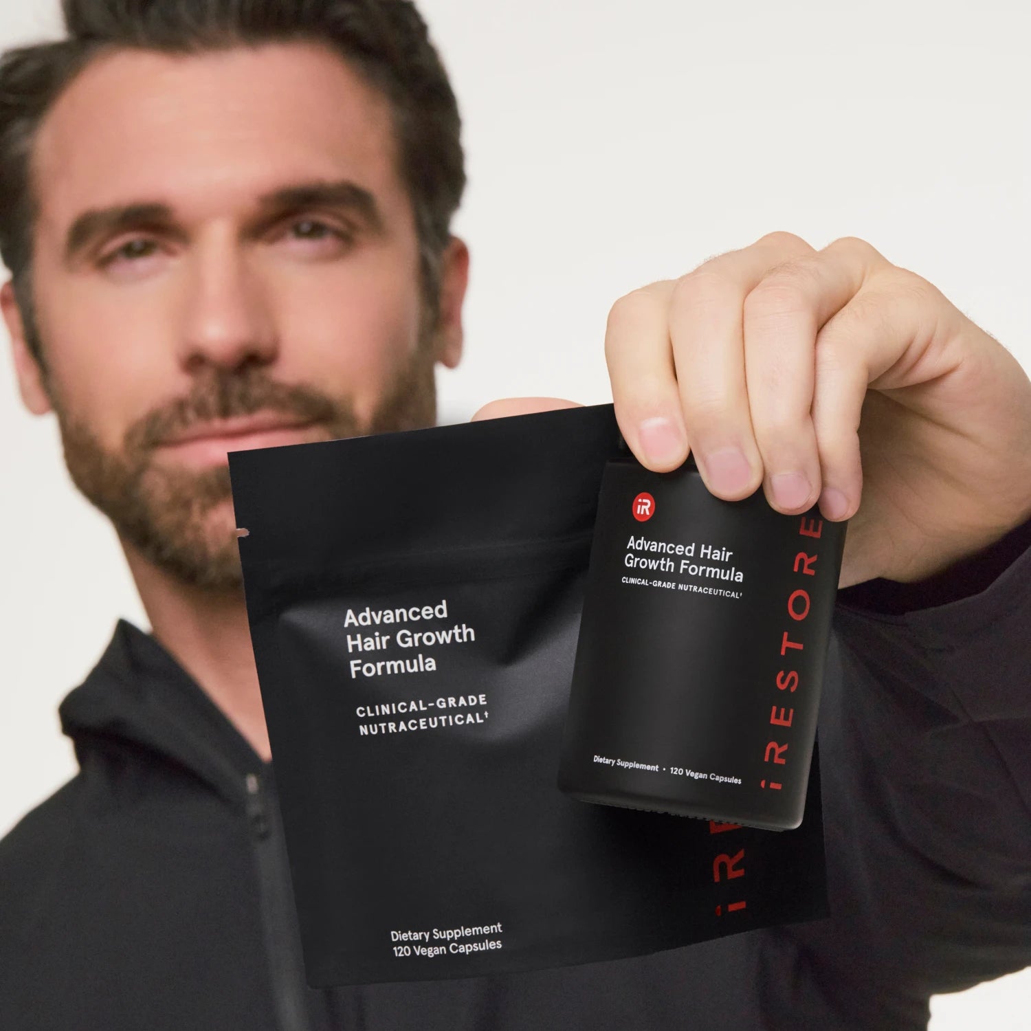 A man holds Advanced Hair Growth Formula against a clean white background.