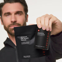 A man holds Advanced Hair Growth Formula against a clean white background.