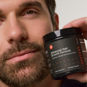 man holding an advanced hair growth formula bottle near his face