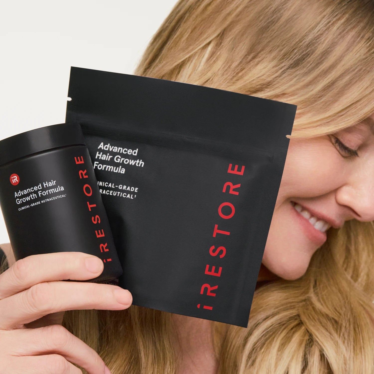 A woman holds Advanced Hair Growth Formula against a clean white background.