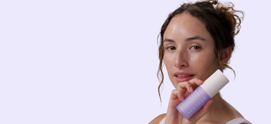 Woman holding a Advanced Retinol Serum against a light purple background