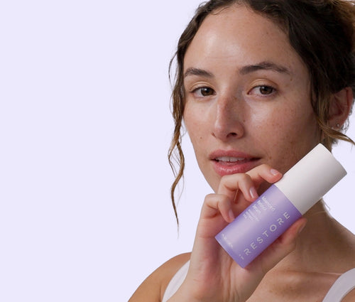 Woman holding a Advanced Retinol Serum against a light purple background