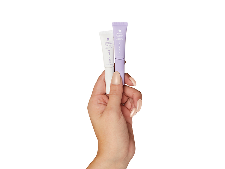 Hand holding eyelash enhancing serum and eyebrow enhancing serum
