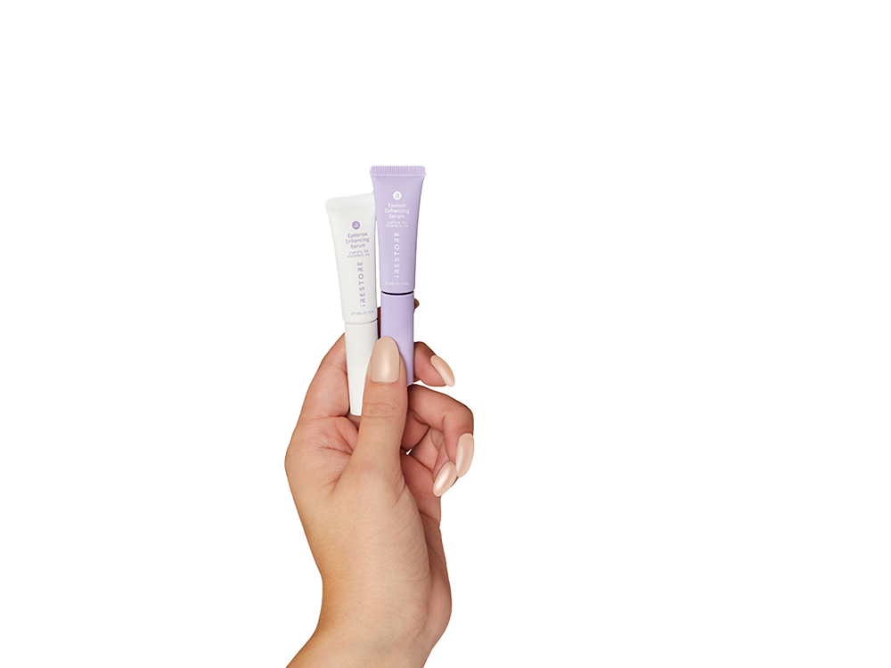 Hand holding eyelash enhancing serum and eyebrow enhancing serum