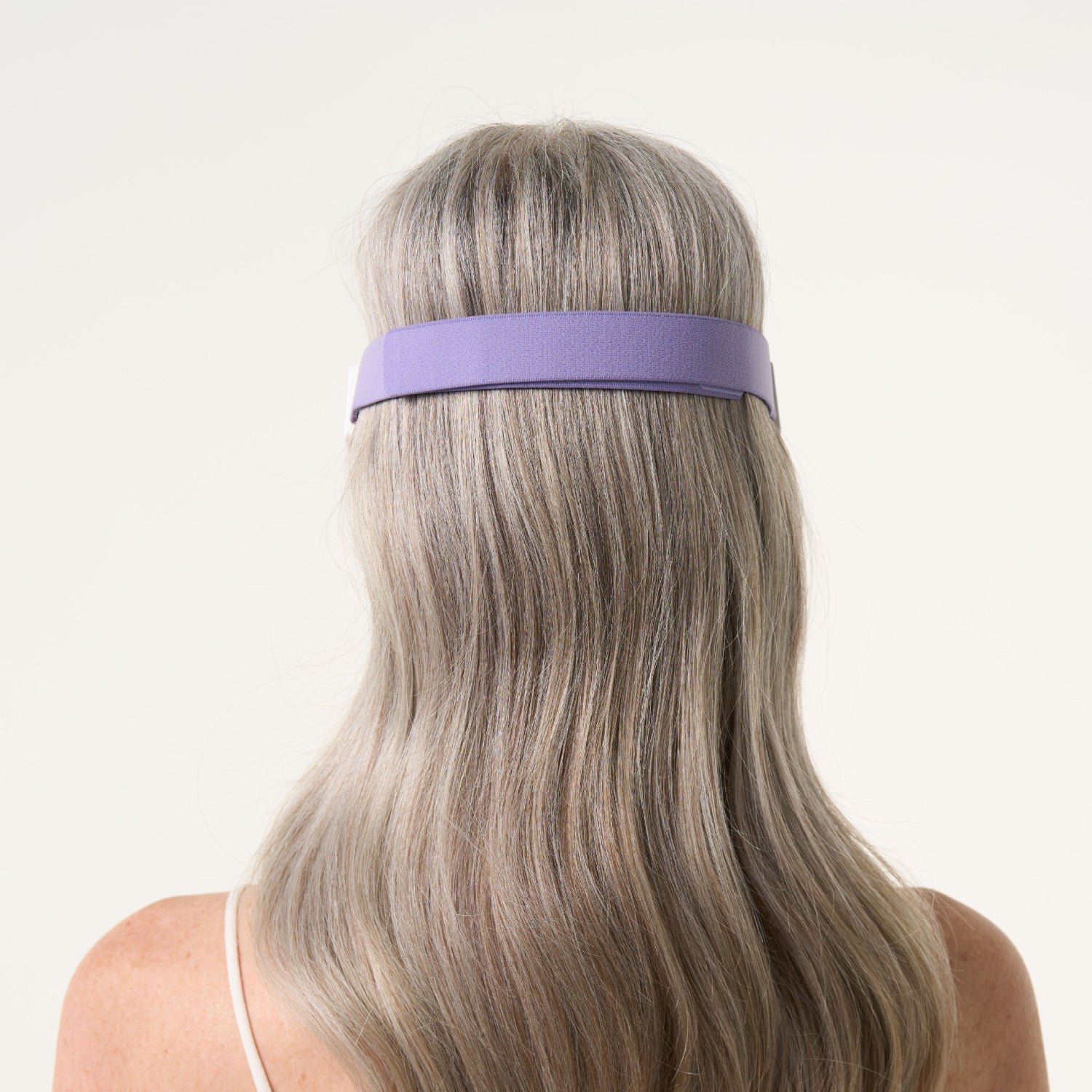 back shot of a woman wearing the LED eye mask where the strap can be seen.