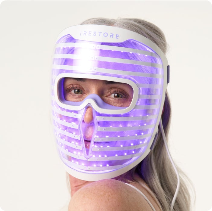 Woman wearing iRESTORE LED facemask with blue light turned on