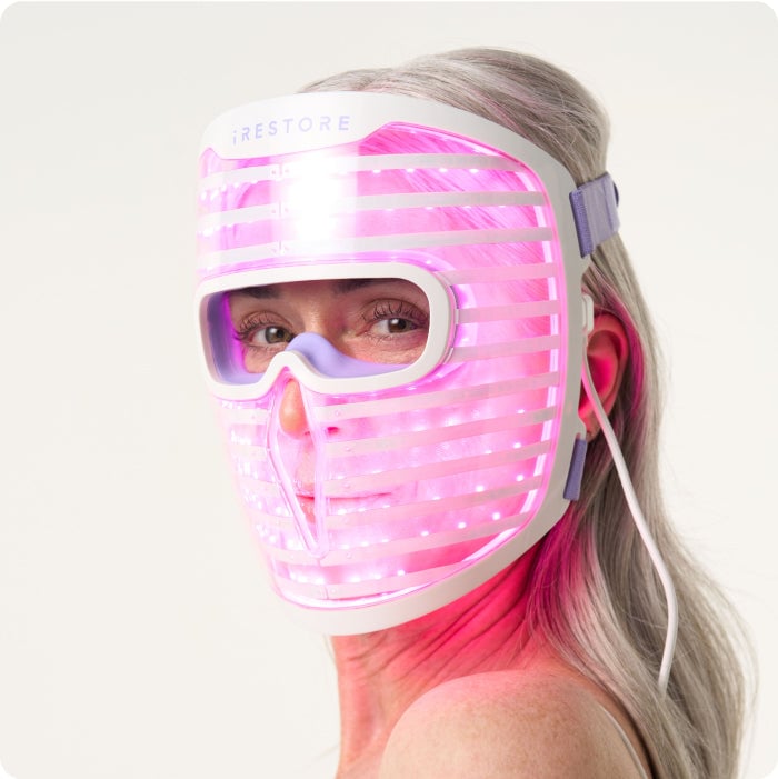 Woman wearing iRESTORE LED facemask with purple light turned on