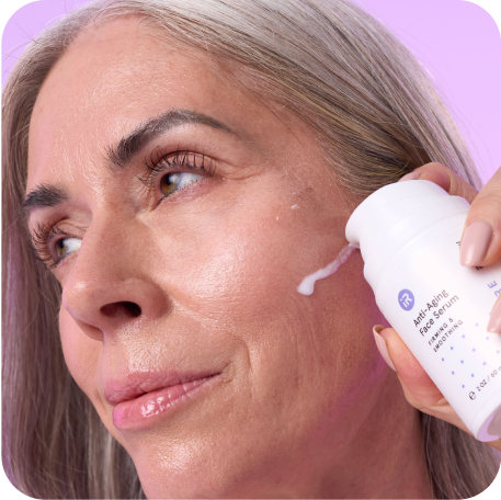 Mature woman putting anti-aging face serum on her face