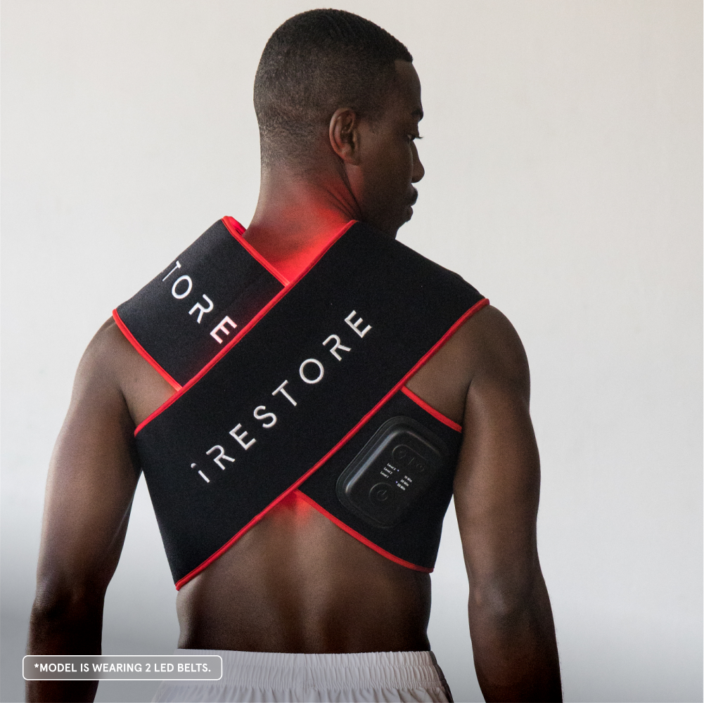 Man wearing a black and red 'iRestore' LED belt on a plain background