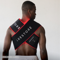 Man wearing a black and red 'iRestore' LED belt on a plain background