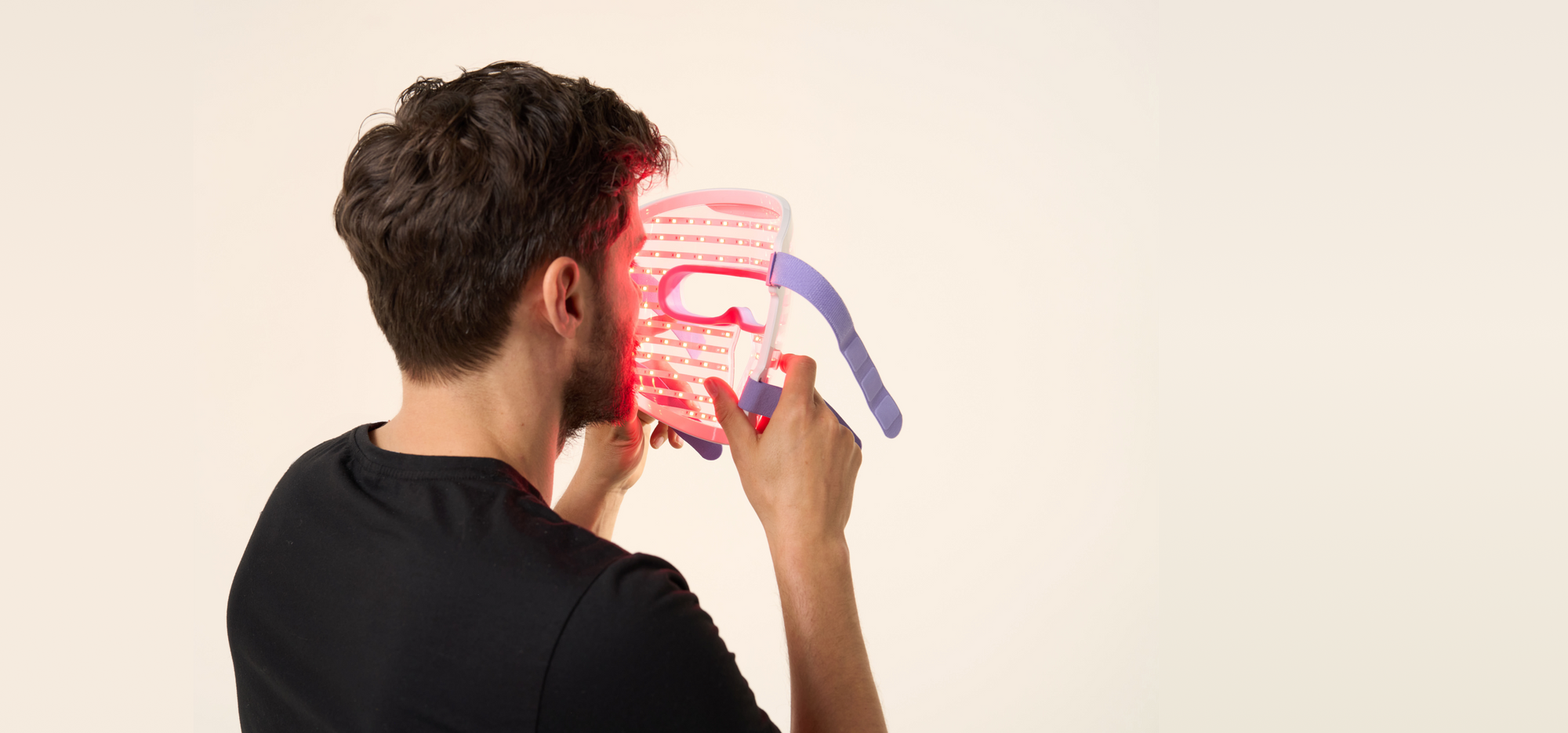 Back view of a man about to wear the LED face mask