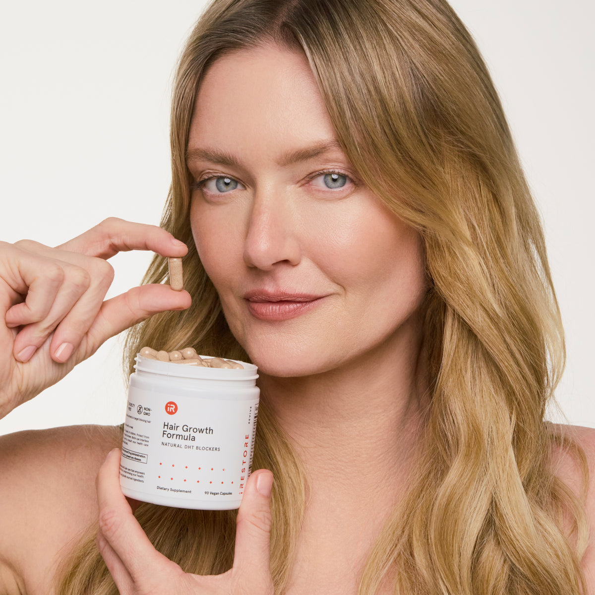 woman taking out a tablet from hair growth formula bottle