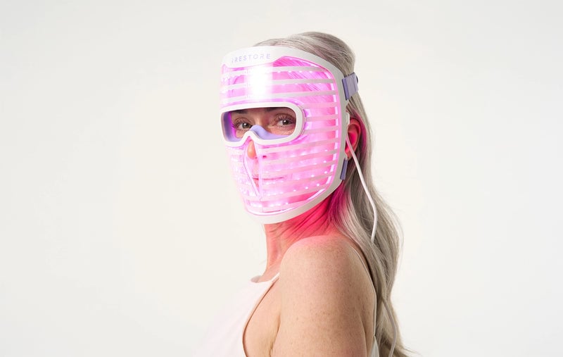 Woman wearing the iRESTORE LED face mask with purple light turned on