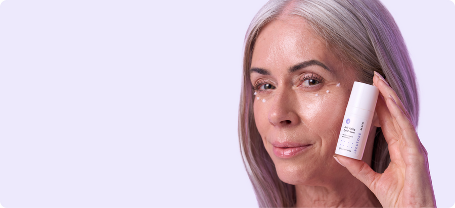 Close up image of a woman holding the Anti-Aging Eye Cream.