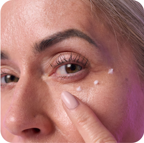 close up shot of woman's face with 3 droplets of anti-aging eye cream under her eyes.