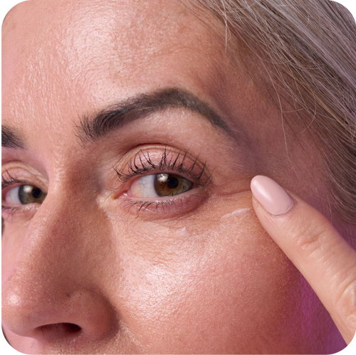 close up shot of woman's face after spreading the eye cream with one finger under her eyes.