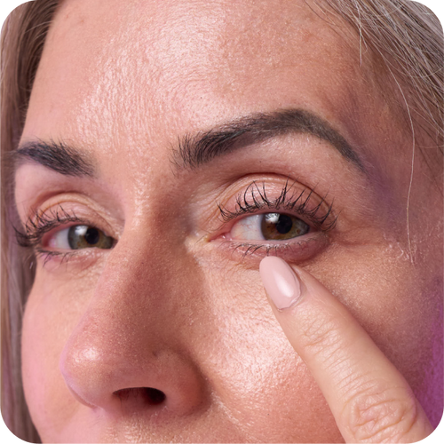 close up shot of woman's face with one finger under her eyes.