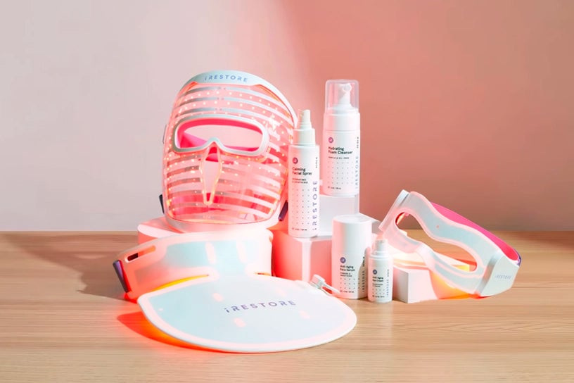 LED face mask, LED neck and chest mask, LED eye mask, Calming facial spray, Hydrating foam cleanser, Anti-aging face serum, and Anti-aging eye cream on top of a wooden table