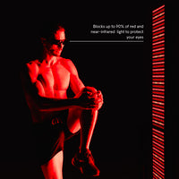 Man wearing protective sunglasses sits in front of a red light therapy panel. Text indicates the eyewear provides 100% protection against UVA/UVB rays.