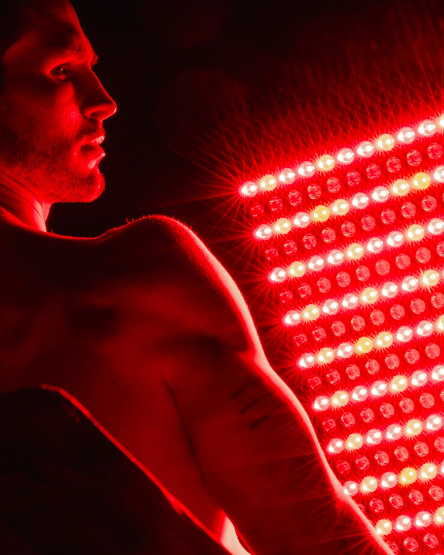 Man sitting in front of a LED light panel emitting red light