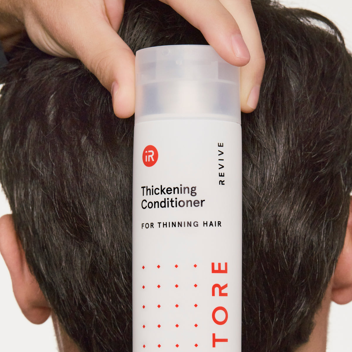 man holding a conditioner bottle behind his head