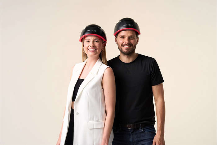 woman and man smiling and wearing iRESTORE Elite on head