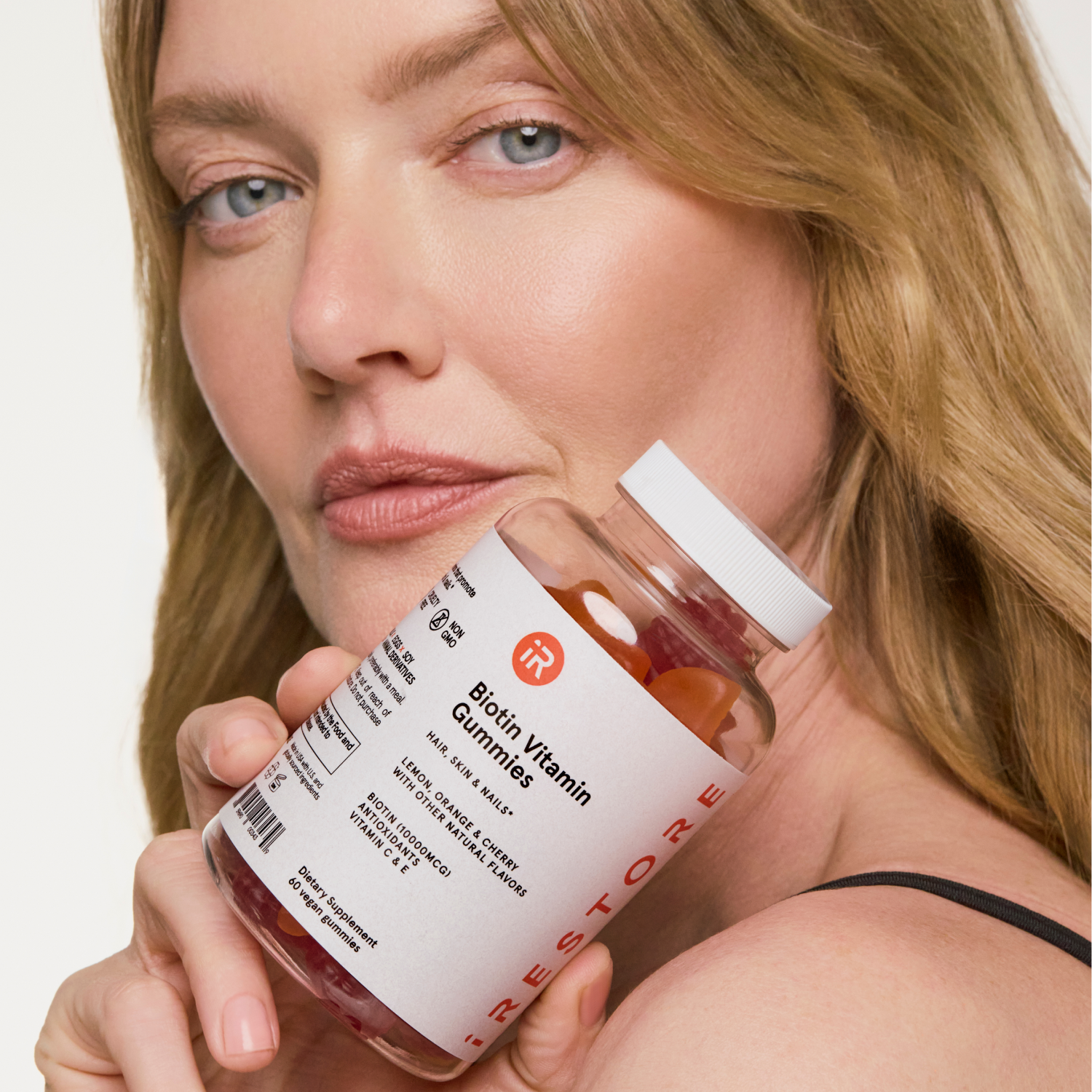 woman holding biotin gummies bottle near her face