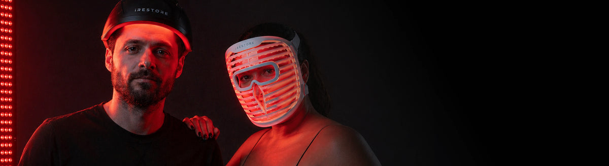 Two people, one wearing a dark cap and the other with a glowing mask, against a dark background.