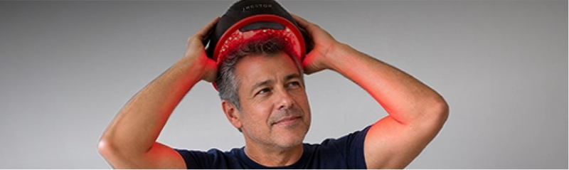 Man using a irestore elite on his head against a gray background