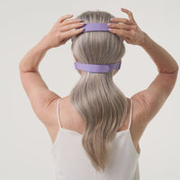 Back view of a woman wearing the iRESTORE LED face mask, adjusting the straps to ensure a secure and comfortable fit