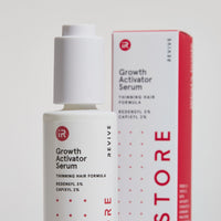 Dropper being pulled out from growth activator serum bottle. Behind, the packaging can be seen.