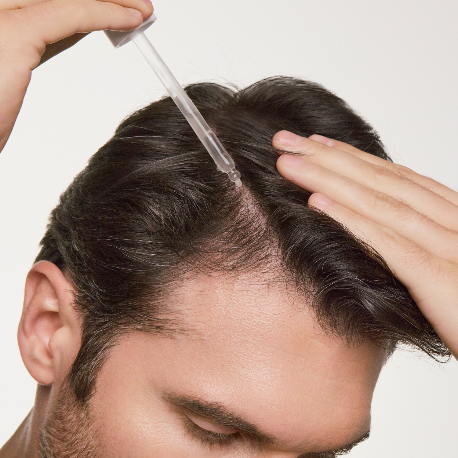 man dropping hair growth serum on his scalp