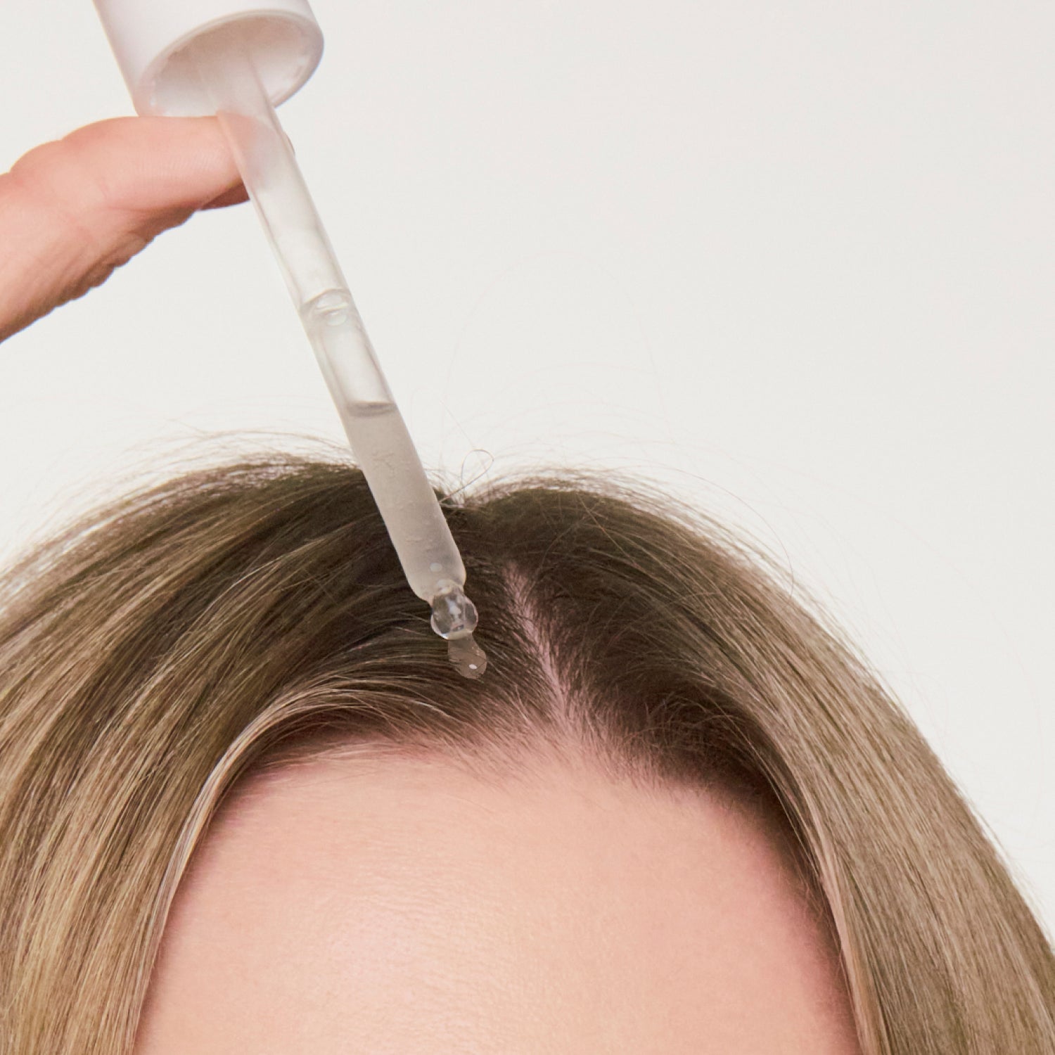 woman dropping hair growth serum on her scalp