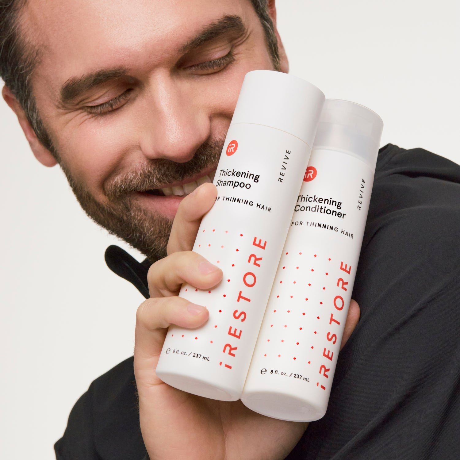 man holding thickening shampoo and conditioner bottles