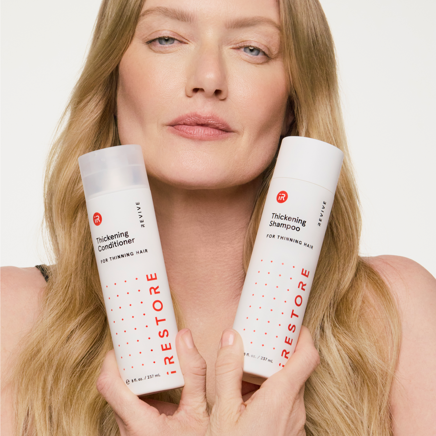 woman holding thickening shampoo and conditioner bottles